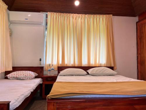 a bedroom with two beds and a window at Lake Homes in Varkala