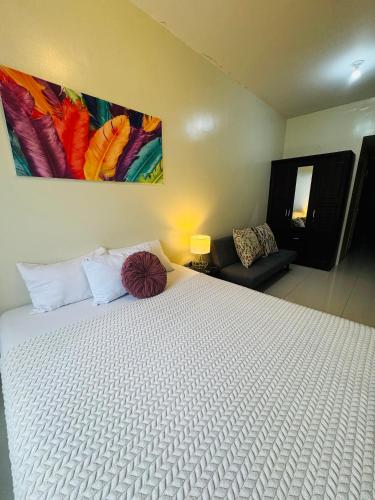 a bedroom with a white bed with a painting on the wall at Brenthill Premium Condo Baguio City with Generator in Baguio
