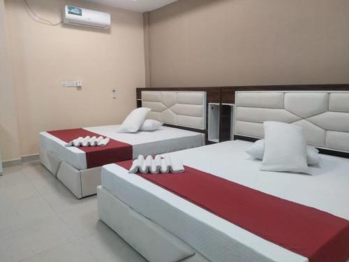 two beds in a room with white and red at Gnaanams Hotel and Restaurant in Jaffna