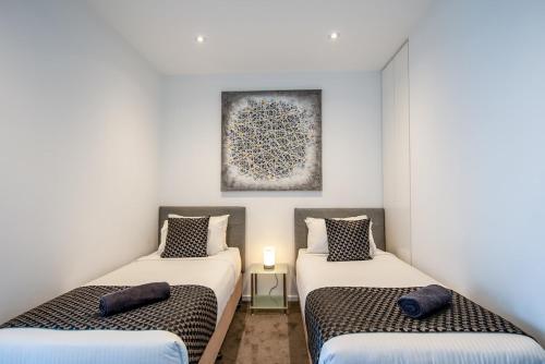 two twin beds in a room with white walls at Prima Tower - Premium Apartment with City and Flames Views in Melbourne