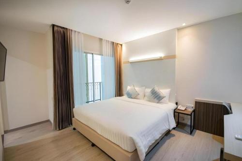 a bedroom with a large white bed and a window at Analynn Hotel in Ban Kohong