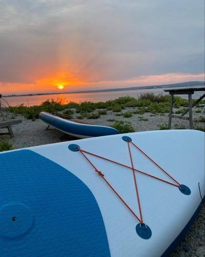 a surfboard on the beach with a sunset in the background at Les pieds dans l’eau in Sète