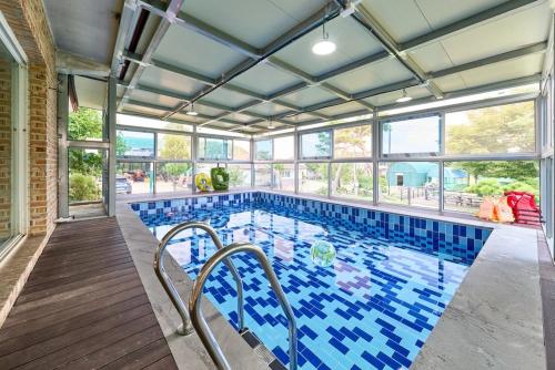 a swimming pool with blue tiles on the floor and windows at Daebudo Nonddureong in Ansan