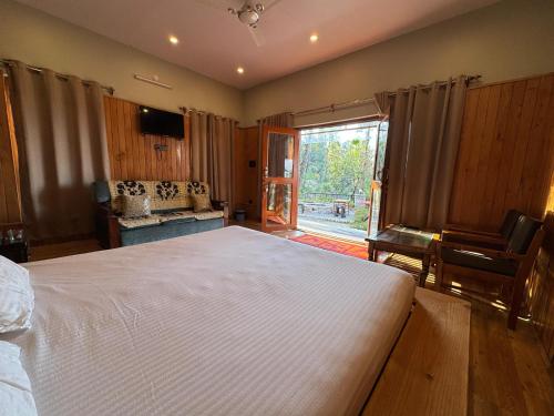 a bedroom with a large bed and a large window at THE HIMALAYAN WOODS, CHAUKORI in Chaukori