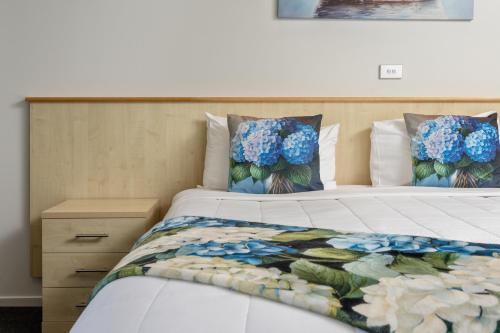 a bedroom with a bed with blue flowers on it at Grove Park Motor Lodge in Blenheim