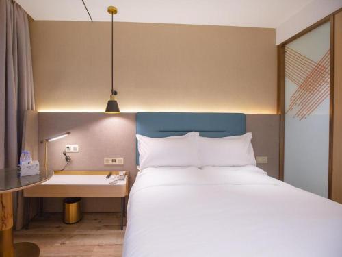 a bedroom with a large bed with a desk and a bed sidx sidx sidx at ZMAX Hotels Shenzhen Lianhuacun Metro Station in Shenzhen