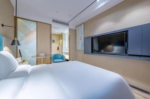 a bedroom with a large white bed and a flat screen tv at ZMAX Hotels Shenzhen Lianhuacun Metro Station in Shenzhen