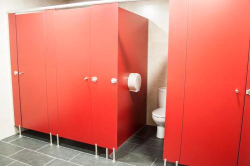 une salle de bains avec des stalles rouges et des toilettes. dans l'établissement De Camino, à Arzúa