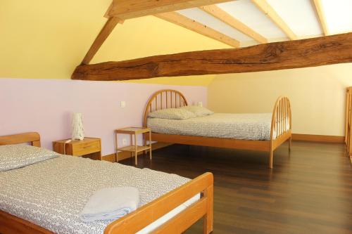 a bedroom with two beds and wooden floors at Gite du Perche in Saint-Ouen-de-Sècherouvre