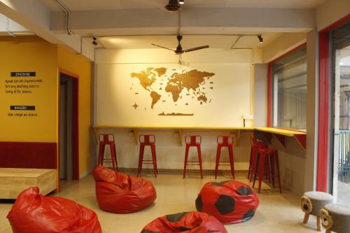 a room with red stools and a world map on the wall at Tokyo Dorms in Kozhikode