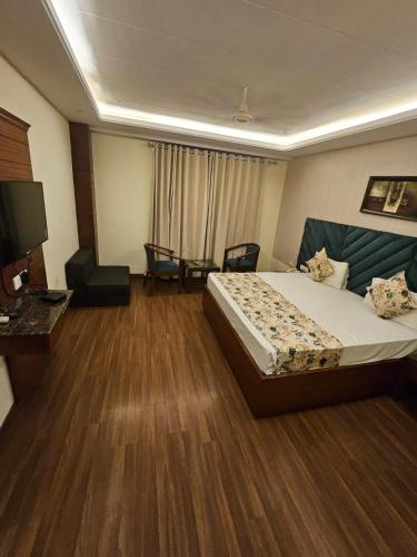a hotel room with a bed and a television at Hotel Paras in Dera Bassi