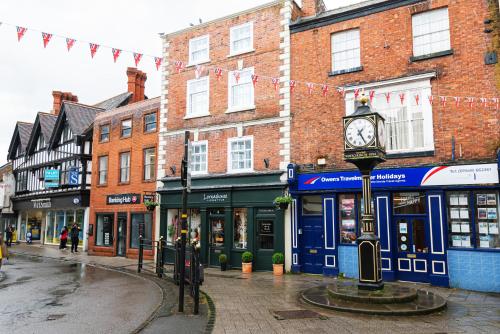 a city street with a clock in front of buildings at Central Whitchurch - Lowcross House Guest Bedroom 1 in Whitchurch