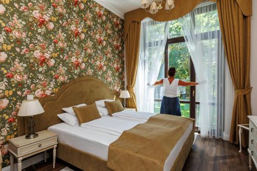 a woman looking out of a window in a bedroom at Tilia Kúria in Bózsva