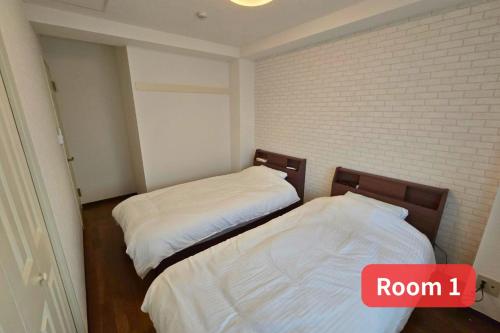 two beds in a room with a brick wall at Vacation House 2 in Funabashi