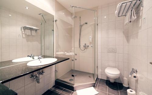 a bathroom with a shower and a sink and a toilet at Motel Fehraltorf in Fehraltorf