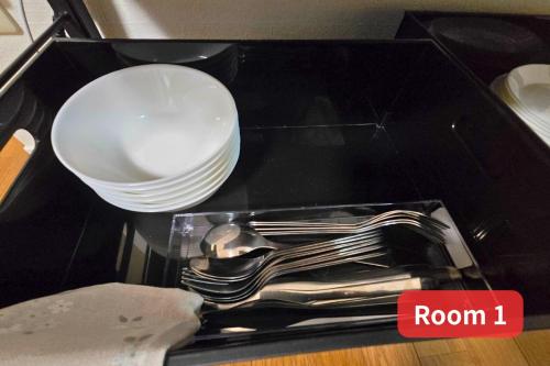 a black table with a plate and bowls and utensils at Vacation House 2 in Funabashi