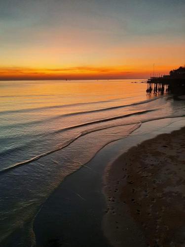 a sunset over a beach with a pier in the water at Karoon Sea View Lodge in Hua Hin