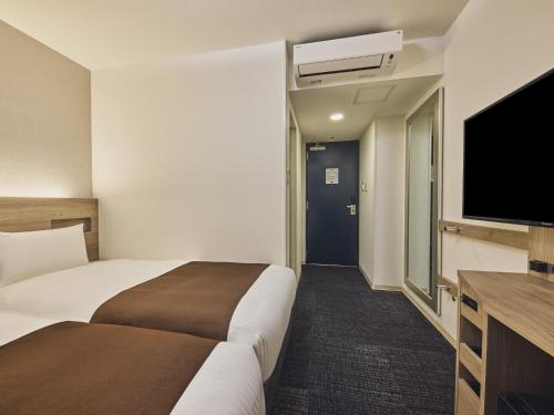 a hotel room with two beds and a flat screen tv at Hotel Villa Fontaine Tokyo-Nihombashi Hakozaki in Tokyo