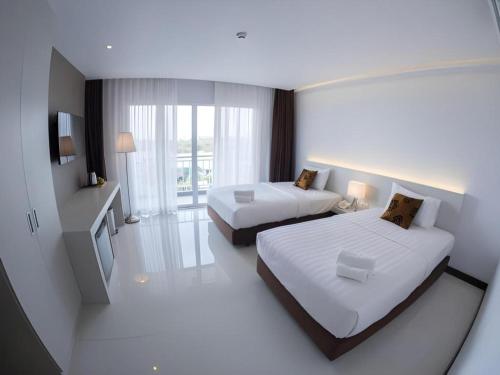 a hotel room with two beds and a television at Chaisaeng Villa in Sing Buri