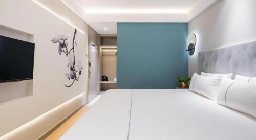 a bedroom with a large white bed and a blue wall at Magnotel Shanghai Henglong Plaza in Shanghai