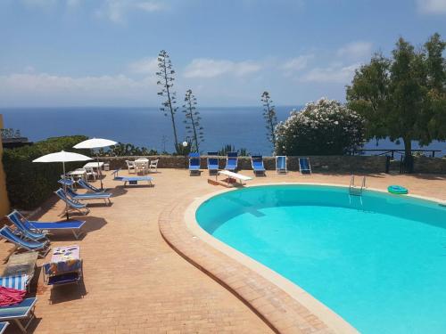 una piscina con sillas y sombrillas junto al océano en Gli Appartamenti degli Dei, en Milazzo