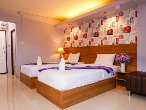 ラムパーンにあるAIRBEST Gemtree Lampang Hotelのベッド2台、ポスター付きの壁が備わるホテルルームです。