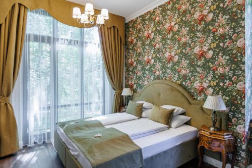 a bedroom with a bed with a floral wallpaper at Tilia Kúria in Bózsva