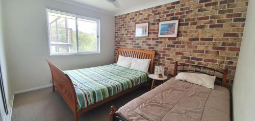 ein Schlafzimmer mit einem Bett und einer Ziegelwand in der Unterkunft Rainbow Cottage - Rainbow Beach. Pets welcome in Rainbow Beach
