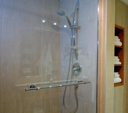 a shower with a glass door in a bathroom at Hôtel Castel in Granby