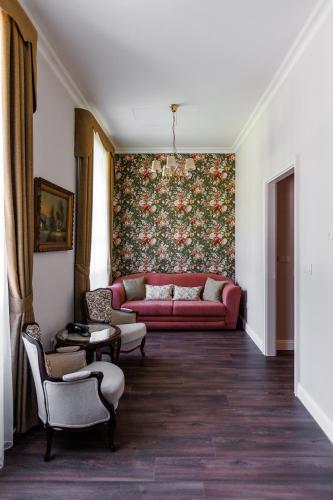 a living room with a red couch and a floral wall at Tilia Kúria in Bózsva