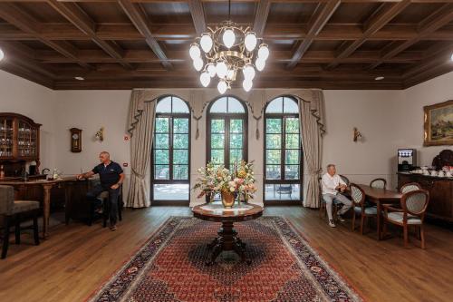 two men sitting in a living room with a table at Tilia Kúria in Bózsva
