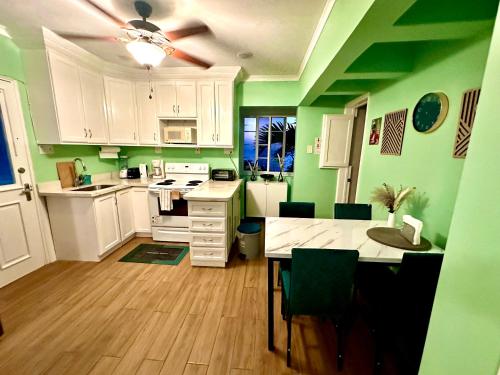 a kitchen with green walls and white cabinets and a table at Gorgeous 1 Bedroom Gem at Negril 7Miles Beach Point Village 