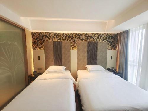 two beds in a hotel room with a window at Jinjiang Metropolo Hotel - Taizhou Wanda Plaza in Taizhou