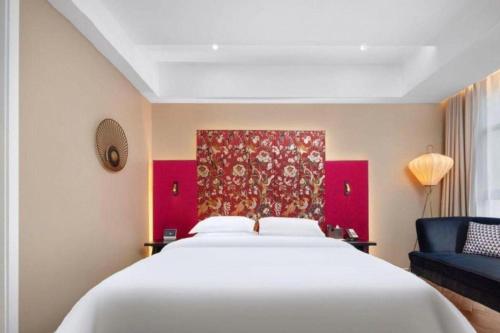 a bedroom with a large white bed and a blue couch at Jinjiang Metropolo Hotel - Taizhou Wanda Plaza in Taizhou