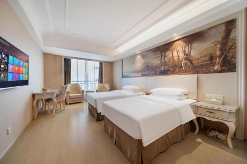 a hotel room with four beds and a painting on the wall at Vienna Hotel Guiyang Jiaxiulou Jichang Road in Guiyang