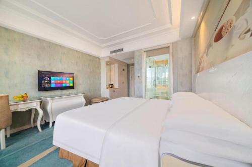 a white bedroom with a large white bed and a desk at Vienna Hotel Guiyang Jiaxiulou Jichang Road in Guiyang