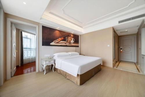 a bedroom with a large bed and a painting on the wall at Vienna Hotel Guiyang Jiaxiulou Jichang Road in Guiyang
