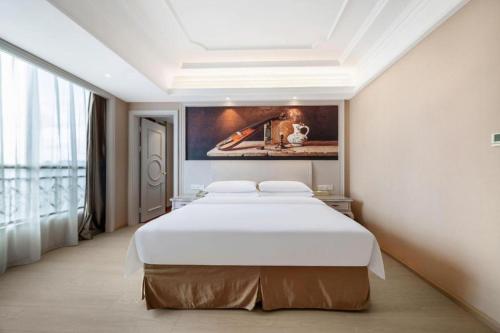 a large bed in a room with a painting on the wall at Vienna Hotel Guiyang Jiaxiulou Jichang Road in Guiyang