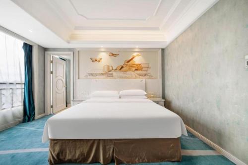 a bedroom with a large white bed in a room at Vienna Hotel Guiyang Jiaxiulou Jichang Road in Guiyang