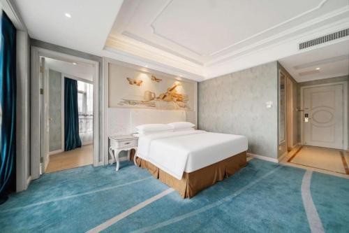 a bedroom with a large white bed and a desk at Vienna Hotel Guiyang Jiaxiulou Jichang Road in Guiyang