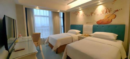 a hotel room with two beds and a guitar on the wall at Vienna Hotel Guiyang Jiaxiulou Jichang Road in Guiyang