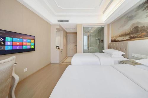 a white room with two beds and a tv at Vienna Hotel Guiyang Jiaxiulou Jichang Road in Guiyang