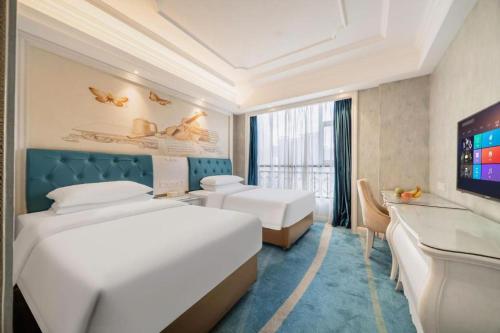 a hotel room with two beds and a flat screen tv at Vienna Hotel Guiyang Jiaxiulou Jichang Road in Guiyang