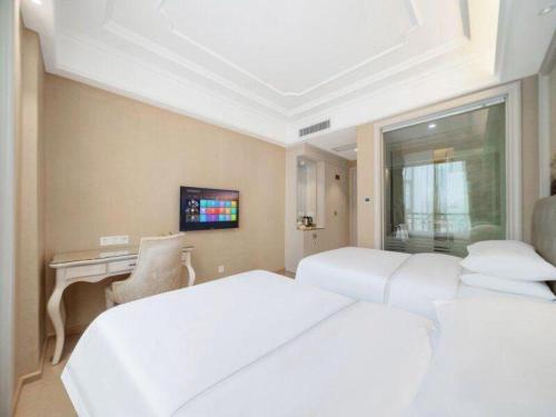 a bedroom with two white beds and a desk at Vienna Hotel Guiyang Jiaxiulou Jichang Road in Guiyang