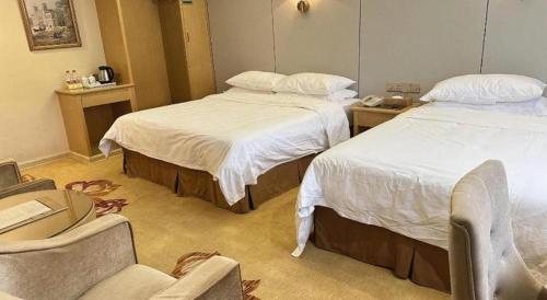 a hotel room with two beds and a chair at Vienna 3 Best Shanghai Baoshan Fengxiang Road in Shanghai