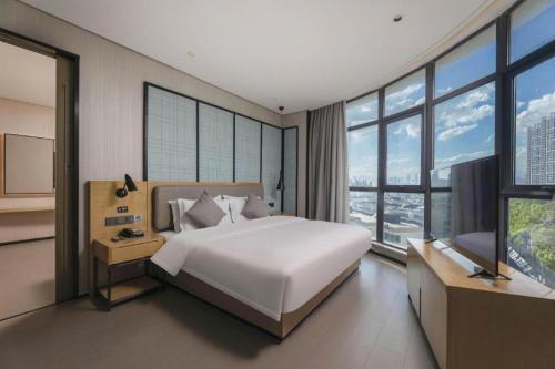 ein Schlafzimmer mit einem großen weißen Bett und großen Fenstern in der Unterkunft Echarm Hotel Wuxi Zhongnan Road Ancient Canal in Wuxi