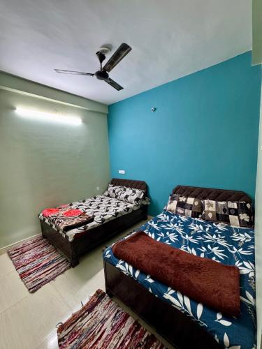 two beds in a room with blue walls at Kaalpeshwar homestay in Ujjain