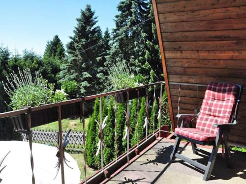 a chair sitting on a porch with a fence at Cozy Forest Hideaway in Suhl in Suhl