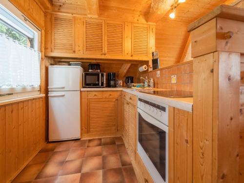 a kitchen with wooden cabinets and a white refrigerator at Cozy Forest Hideaway in Suhl in Suhl