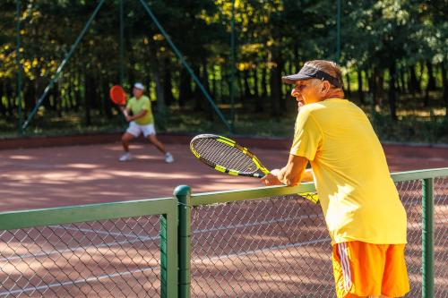 a man holding a tennis racket on a tennis court at Tilia Kúria in Bózsva